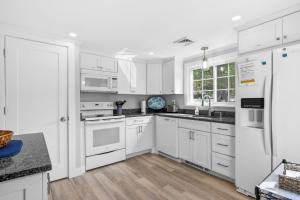 a white kitchen with white appliances and wooden floors at 25 Grey Neck Road West Harwich Cape Cod - - Crosswinds II in West Harwich