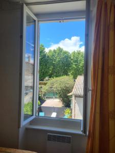 an open window with a view of a yard at Appartement avec piscine partagée in Boucoiran-et-Nozières