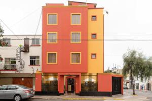 a red and yellow building with a car parked in front at Kontiki Miraflores in Lima