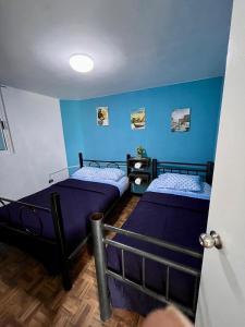 two beds in a room with blue walls at Hospedaje Casa Azul in Mexico City
