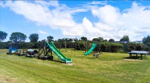 a playground with a green slide in a field at Mobil home familial in Talmont