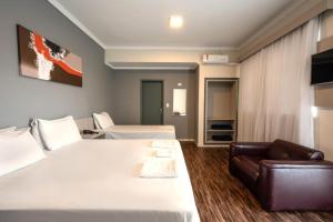 a hotel room with two beds and a couch at Italian Palace Hotel Rede Carlton in Três Corações