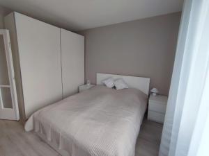 a white bedroom with a white bed with two pillows at Feels like home Paks in Paks