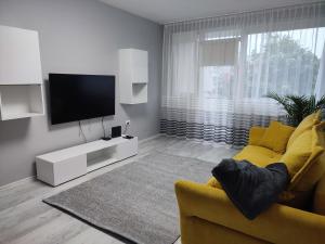 a living room with a yellow couch and a flat screen tv at Feels like home Paks in Paks