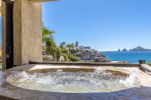 a fountain in a patio with the ocean in the background at Stunning 2 BR with Ocean Views & Jacuzzi by the Beach in Cabo San Lucas