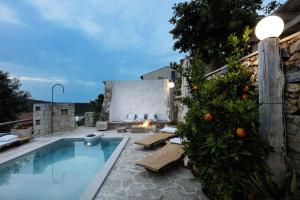 a swimming pool with an orange tree next to a fireplace at Antonia's stonebuilt mansion with a private pool in Arménoi