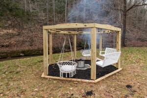 een prieel met 2 stoelen en een schommel bij Hot Tub - Fire Pit - River - State Park - King Bed in Wingina
