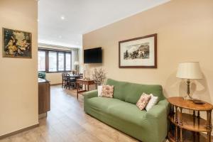 a living room with a green couch and a dining room at ROMAN DREAM I in Rome