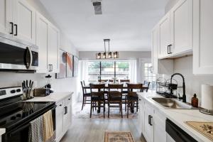 a kitchen with white cabinets and a dining room at Modern Paradise Hot Tub Game Room Swing Set Bbq in San Antonio