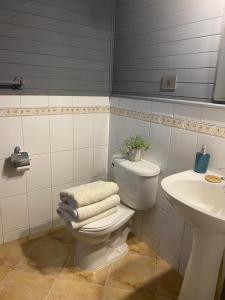 a bathroom with a toilet and a sink with towels at Raki Bed and Breakfast Hostel in Trape