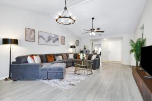 a living room with a blue couch and a tv at Modern Paradise Hot Tub Game Room Swing Set Bbq in San Antonio +42 photos