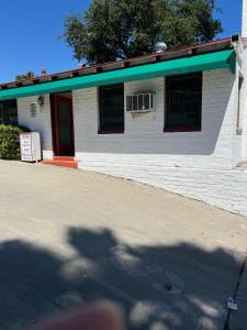 a white building with a green roof at El Rio Motel in Glendale