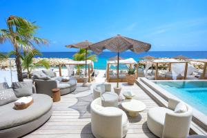 a resort with a pool with white furniture and the ocean at Art Hotel Curacao - Luxury Adults Only in Willemstad