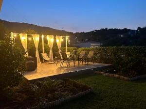 a wooden deck with chairs and a table with lights at La Casa Tzortzina in Kokkino Nero