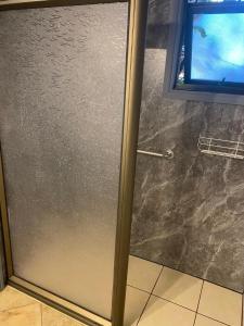 a glass shower door in a bathroom with a window at Raki Bed and Breakfast Hostel in Trape