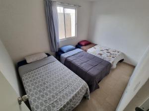 zwei Betten in einem kleinen Zimmer mit Fenster in der Unterkunft Hacienda de Cortés in Tlacote el Bajo