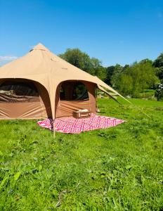 a tent sitting in the grass in a field at Goldings Farm yurt Tent firepit bbq activities in Bramfield