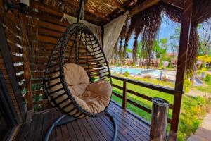a swinging chair on a porch with a view of a pool at Kerpe Bungalov Hotel in Kocaeli