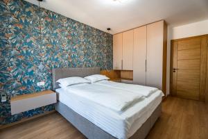 a bedroom with a large bed with a floral wallpaper at Bloom Apartment - City Center in Gjakove