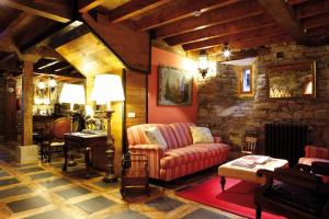Hotel Rural Casa Xusto في لا كاريداد: غرفة معيشة مع أريكة وجدار حجري