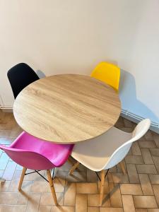 a wooden table with four colorful chairs around it at Chez Diane , appartement complet , parking gratuit devant l'immeuble in Colmar +15 photos