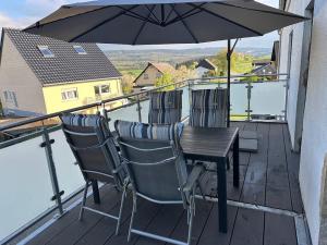 a table and chairs on a balcony with an umbrella at Ferienwohnung Hochwaldblick 4 in Morbach