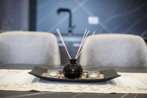 a black vase sitting on a table with two cups at Valbona Apartament's 2 in Vlorë