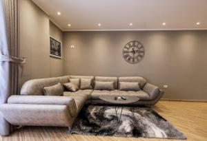 a living room with a couch and a clock on the wall at Valbona Apartament's 2 in Vlorë