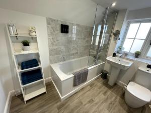 W łazience znajduje się wanna z prysznicem i umywalka. w obiekcie Spacious Family Friendly Cottage w mieście Tarporley +30 zdjęć