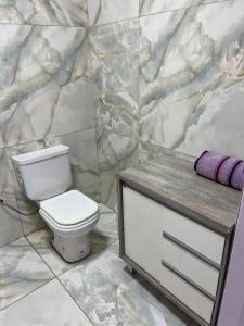 a bathroom with a toilet and a marble wall at Departamento Puerto Esperanza in La Porteña