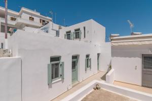 a white building with green doors and windows at Lapis Domus Milos in Plaka Milou