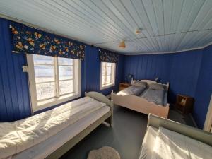 a bedroom with two beds and a blue wall at Selnestun in Selnes