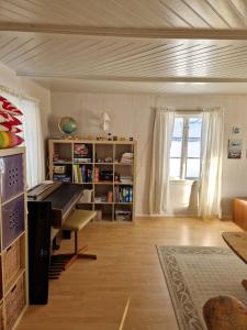 a living room with a piano and a book shelf at Selnestun in Selnes