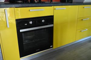 a yellow kitchen with a black oven in it at Evo Moonlight by the sea in Mamaia +5 photos