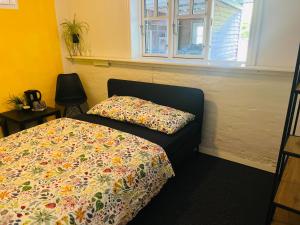 a bedroom with a bed with a flowered blanket and a window at Hygge i det grønne in Langå