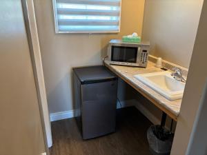 a kitchen with a counter with a microwave and a sink at Seven Oakes Motel in Kingston