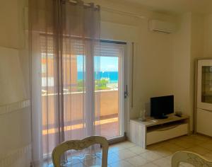 een woonkamer met een raam met uitzicht op de oceaan bij MIRA IL MARE Seaview Apartment - Sunset Lovers' Spot - 50m from the Beach LAVINIO MARE in Anzio