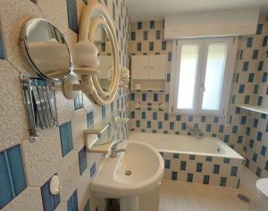 een badkamer met een wastafel, een spiegel en een bad bij MIRA IL MARE Seaview Apartment - Sunset Lovers' Spot - 50m from the Beach LAVINIO MARE in Anzio +19 foto's