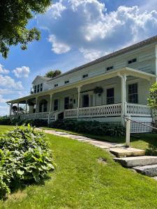 a large white house with a porch and a yard at Hoppy Hill Farm House in Dover Plains