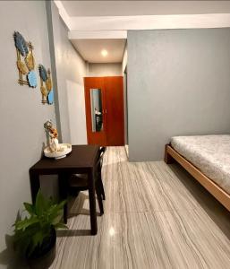 a small room with a bed and a table and a desk at Shanti's Inn in General Luna