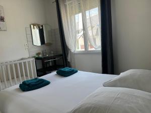 una camera da letto con un letto con due asciugamani blu sopra di Maison familiale à Morgat, jardin clos, à 2 minutes de la plage a Crozon