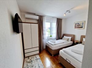 a hotel room with two beds and a window at Apartment Pacifik Lux & Private Garage in Sarajevo