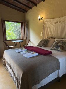 une chambre avec un grand lit avec des serviettes dessus dans l'établissement Ecocentro Brasil - Bangalô 2, à São Pedro