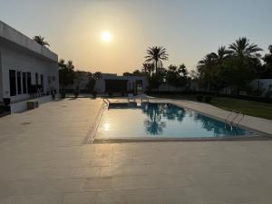 a swimming pool with the sun setting in the background at Radiance Holiday Resort Muscat in Seeb