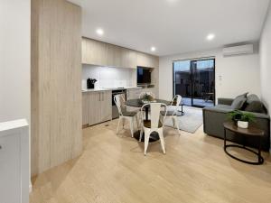 a kitchen and living room with a table and a couch at Spacious Allen Street 1BR Stay in Christchurch