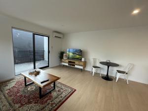 a living room with a table and a tv at Relaxing CBD Getaway in Christchurch