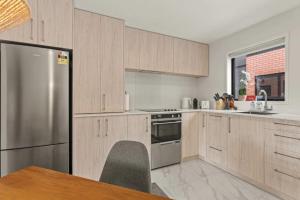 a kitchen with wooden cabinets and a stainless steel refrigerator at Warm and Bright 2 Bed Townhouse in Auckland