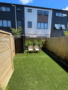 un patio trasero con una valla, una mesa y sillas en Well-furnished Auckland Stunner, en Auckland