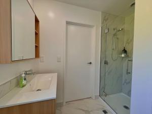 a white bathroom with a sink and a shower at Cosy City Centre Studio in Christchurch