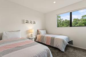 Dos camas en una habitación blanca con ventana. en Charming 2 Bed Family Home, en Auckland